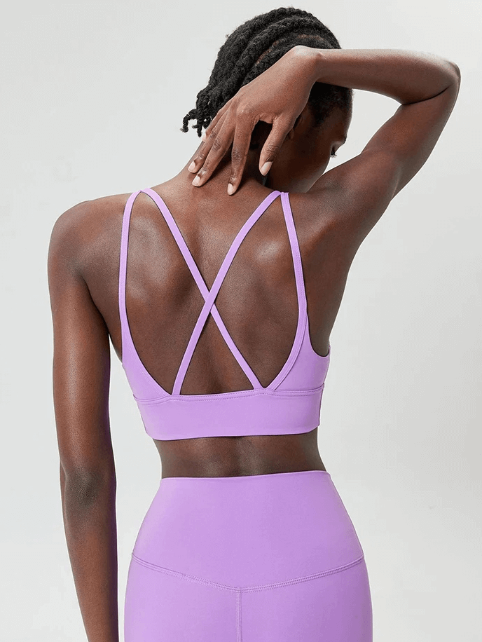 Woman wearing vibrant solid color sports bra with sexy cross-back design, ideal for intense workouts in breathable fabric.